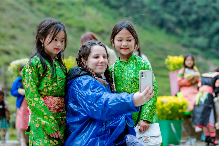 A tourist taking photos with two ethnic minority girls in Ha Giang